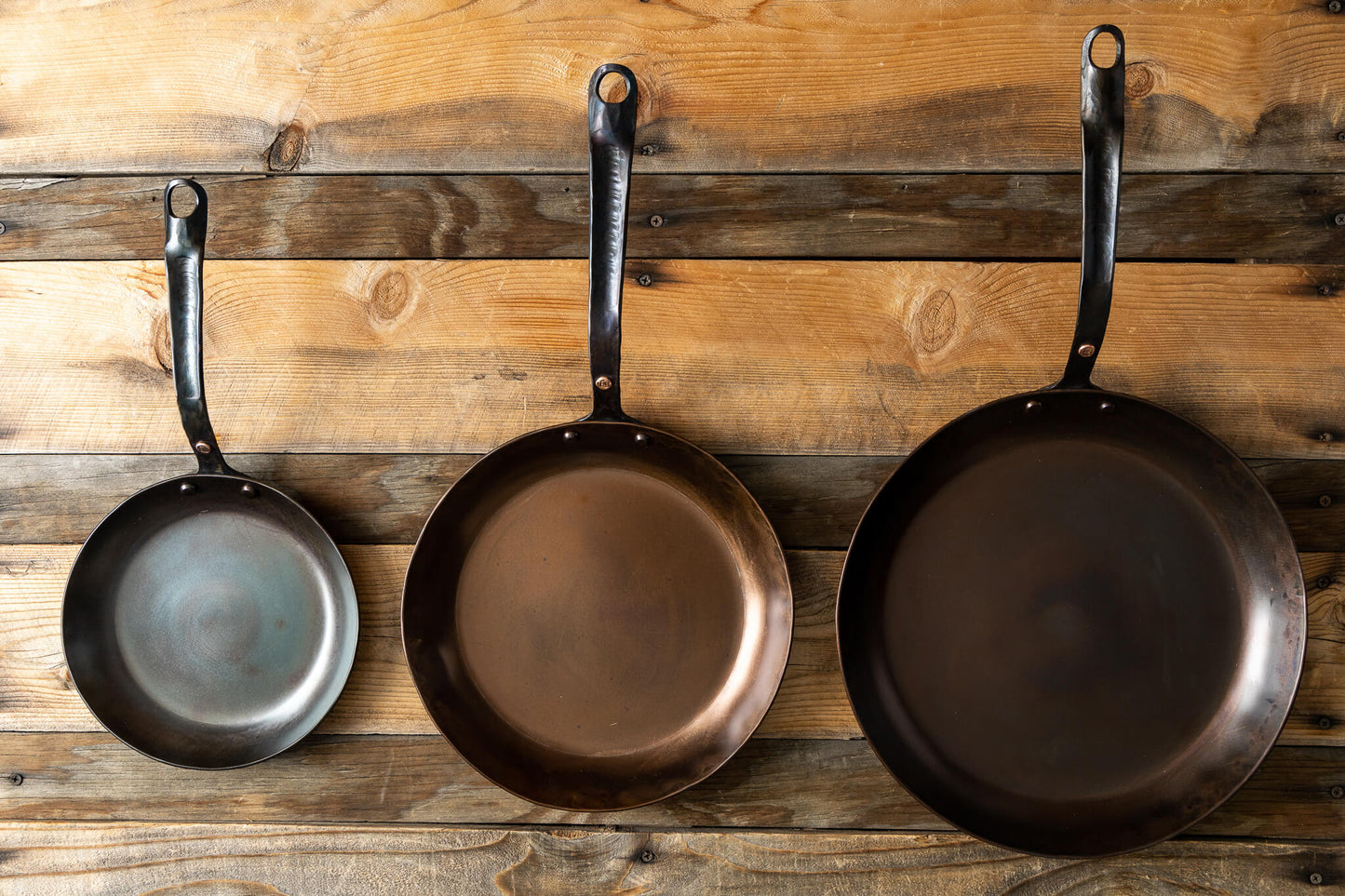 https://copperstateforge.com/cdn/shop/products/forged-round-pans-set-top-wood-background.jpg?v=1653866199&width=1445